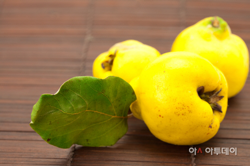 yellow quinces with a green leaf on a bamboo mat