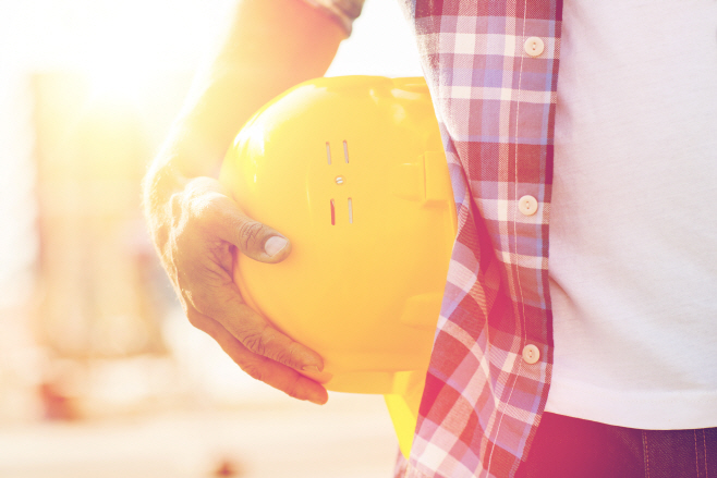 close up of builder hand holding hardhat outdoors