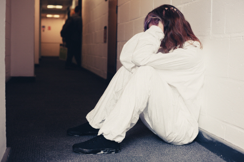 Upset woman in boiler suit sitting in corridor