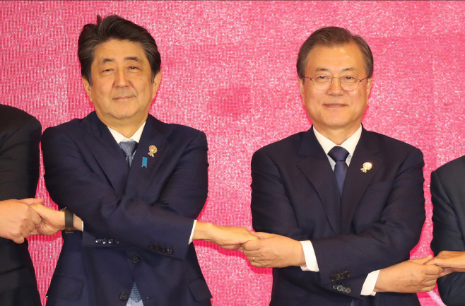 어색한 표정으로 손잡은 문 대통령과 아베 총리,