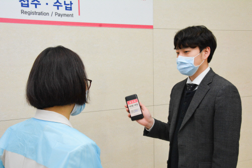 출입구에서 모바일출입증 보여주는 환자