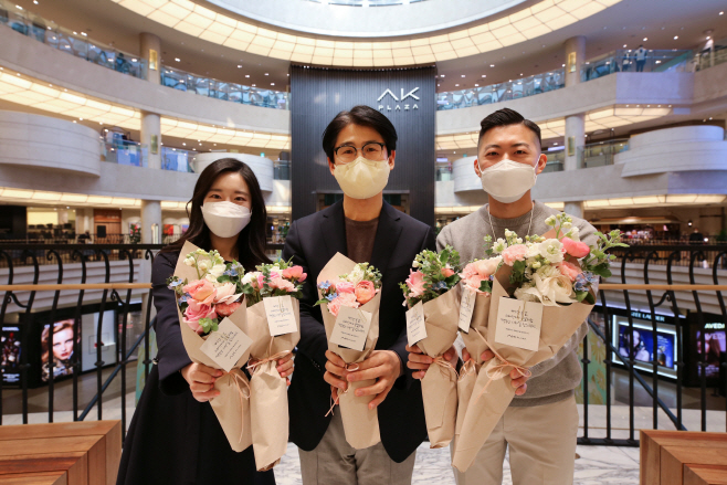 AK플라자 김재천대표가 직원들과 꽃다발을 들고 웃고있다