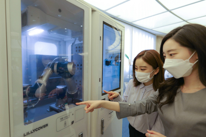 고객들이 화장품을 만들고 있는 스마트팩토리를 지켜보고 있다