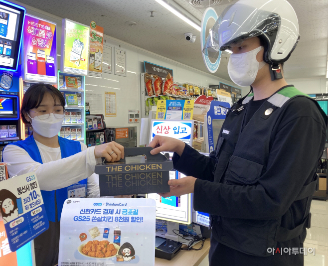 GS25 직원이 쏜살치킨을 전문 배달원에게 전달하고 있다
