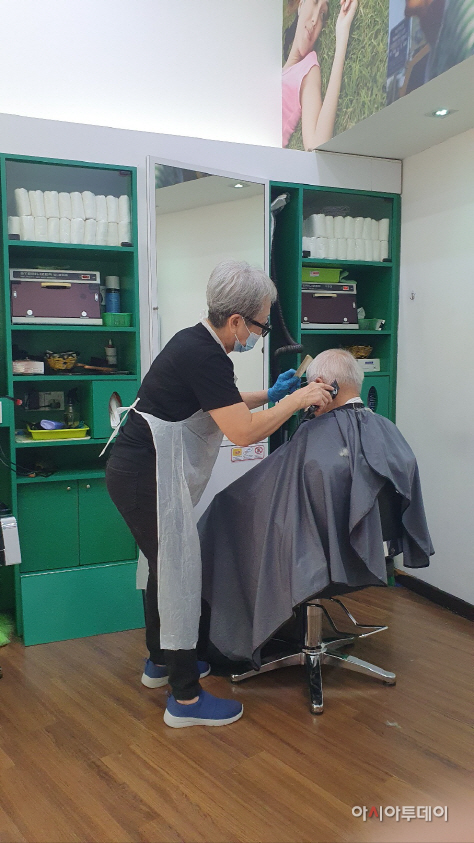 말레이시아 여성 리타(60)씨가 미용실에서 손님의 머리를 자르