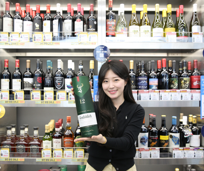 모델이 GS25에서 위스키 상품을 들고 포즈를 취하고 있다