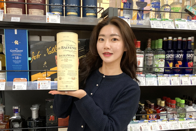 모델이 GS25에서 발베니 위스키를 들고 포즈를 취하고 있다
