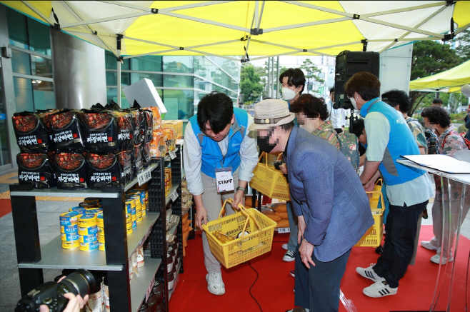 사진2. 물품을 고르고 있는 어르신과 이를 돕는 자원봉사자