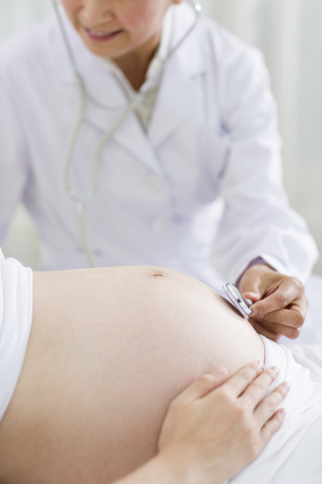 Doctor examining pregnant woman at home