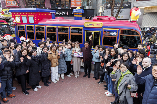 (우) 박강수 마포구청장이 마포순환열차버스 앞에서 환하게 손을 들어보이고 있다.