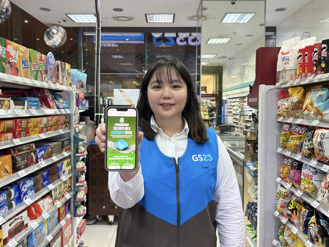[이미지1] GS25 근무자가 우리동네GS 앱에서 진행 중인 사전예약 기획전 행사를 펼쳐 보이고 있다.