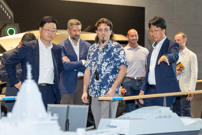 사진. 6일(수) HD현대 글로벌R&D센터를 방문한 팔머 럭키(Palmer Luckey) 안두릴 공동설립자가 HD현대가 개발 중인 무인수상정에 대한 설명을 듣고 있다. 사진 앞줄 왼쪽부터 주원호