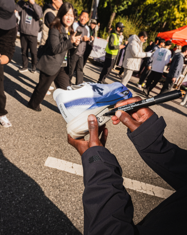 데상트 러닝화 '델타프로 EXP V3' (우승한 선수가 러닝화에 사인을 하는 모습)