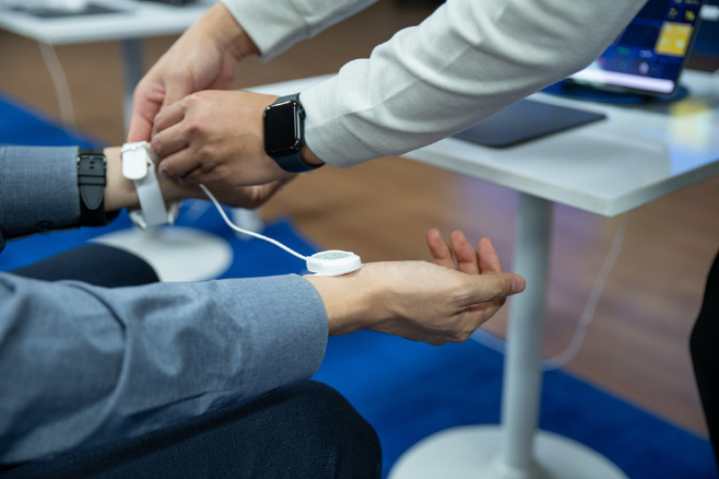 [사진자료 3] 한 참관객이 AF Summit 2025에서 열린 대웅제약 디지털 헬스존에서 웨어러블 심전도 기기를 착용해 보고 있다.