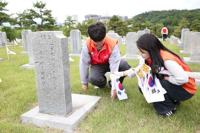 사진. SKC 구성원들이 국립서울현충원 묘비 앞에 태극기를 꽂으며 묘역 정화 활동을 실시하고 있다.