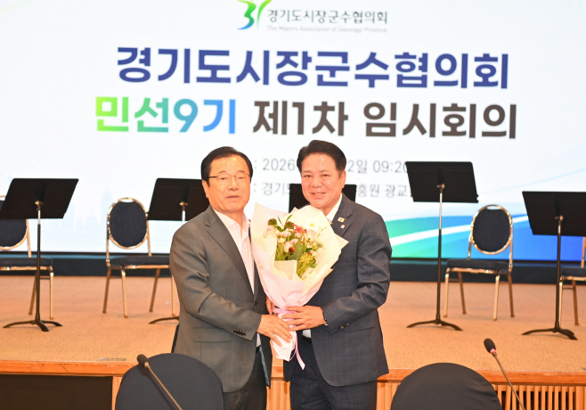 민선9기 경기도시장군수협의회장으로 선출된 최대호 안양시장(오른쪽)이 임시회장으로서 회의를 진행한 이현재 하남시장(왼쪽)으로부터 꽃다발을 받고 있다